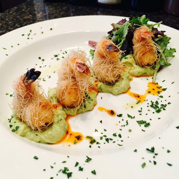 Four crispy shrimp wrapped in noodles, served on avocado puree with greens and chili oil.